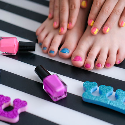 Children's feet with bright pedicure and manicure